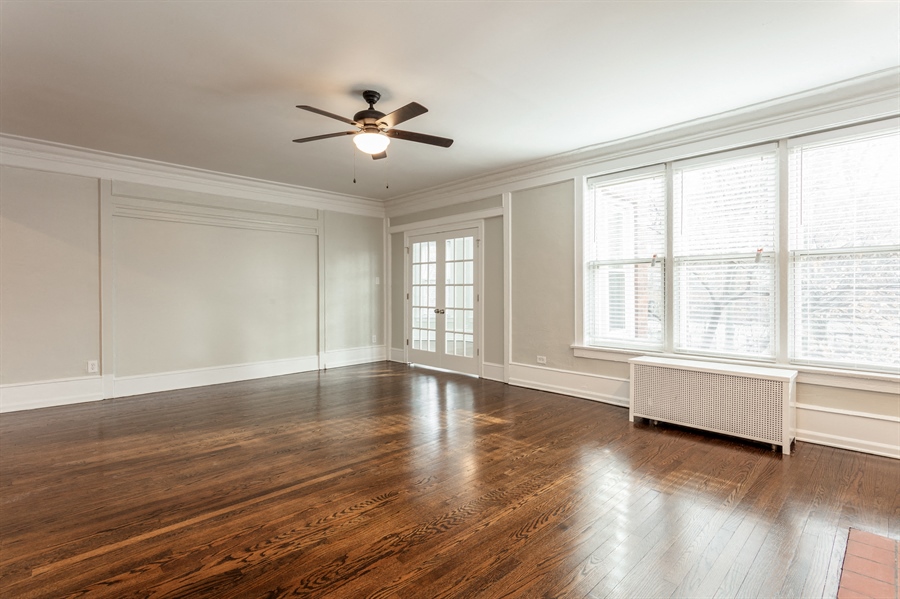 an empty living room with wood floors and a ceiling fan