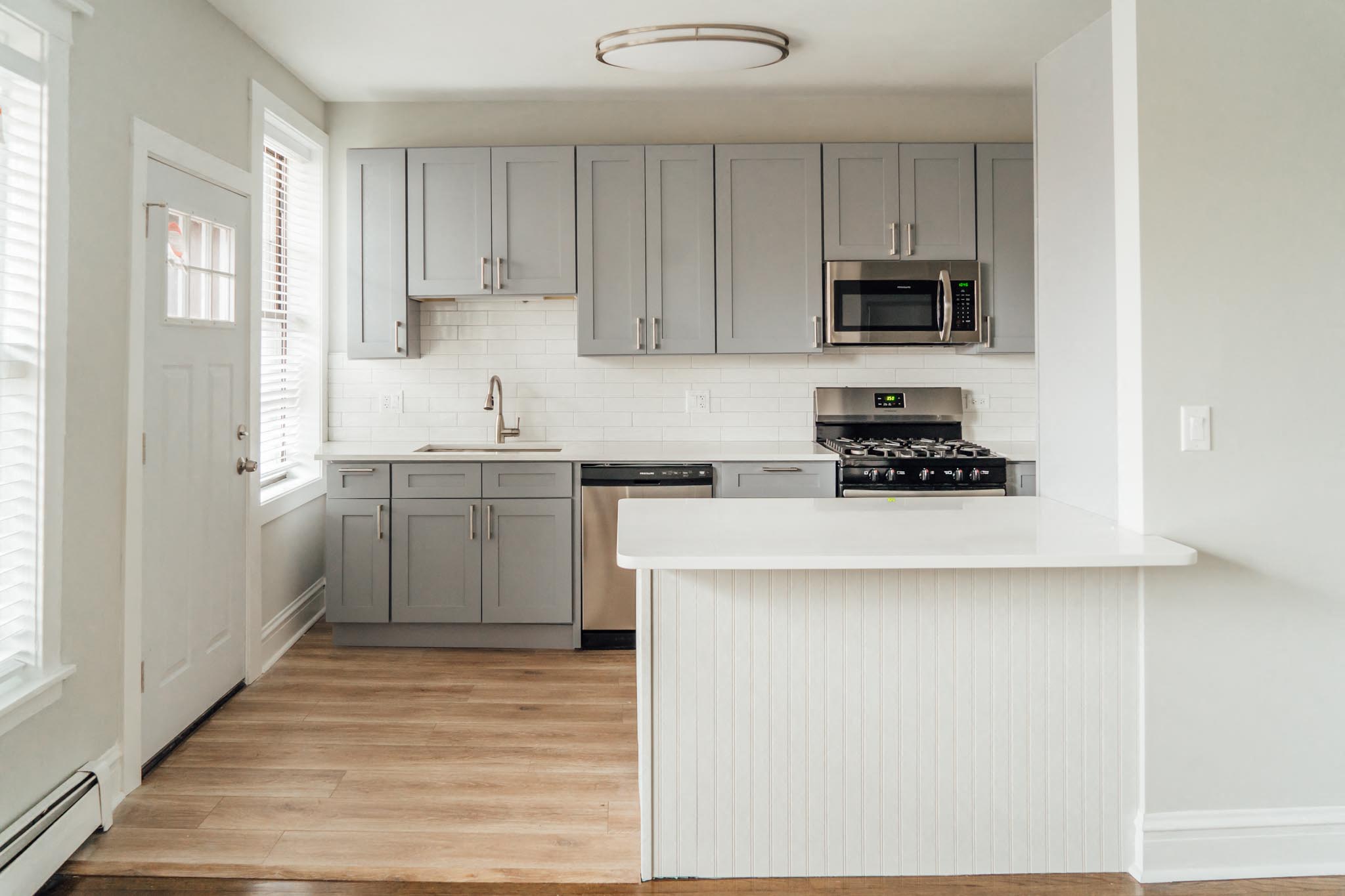 a white kitchen with gray cabinets and a white counter top