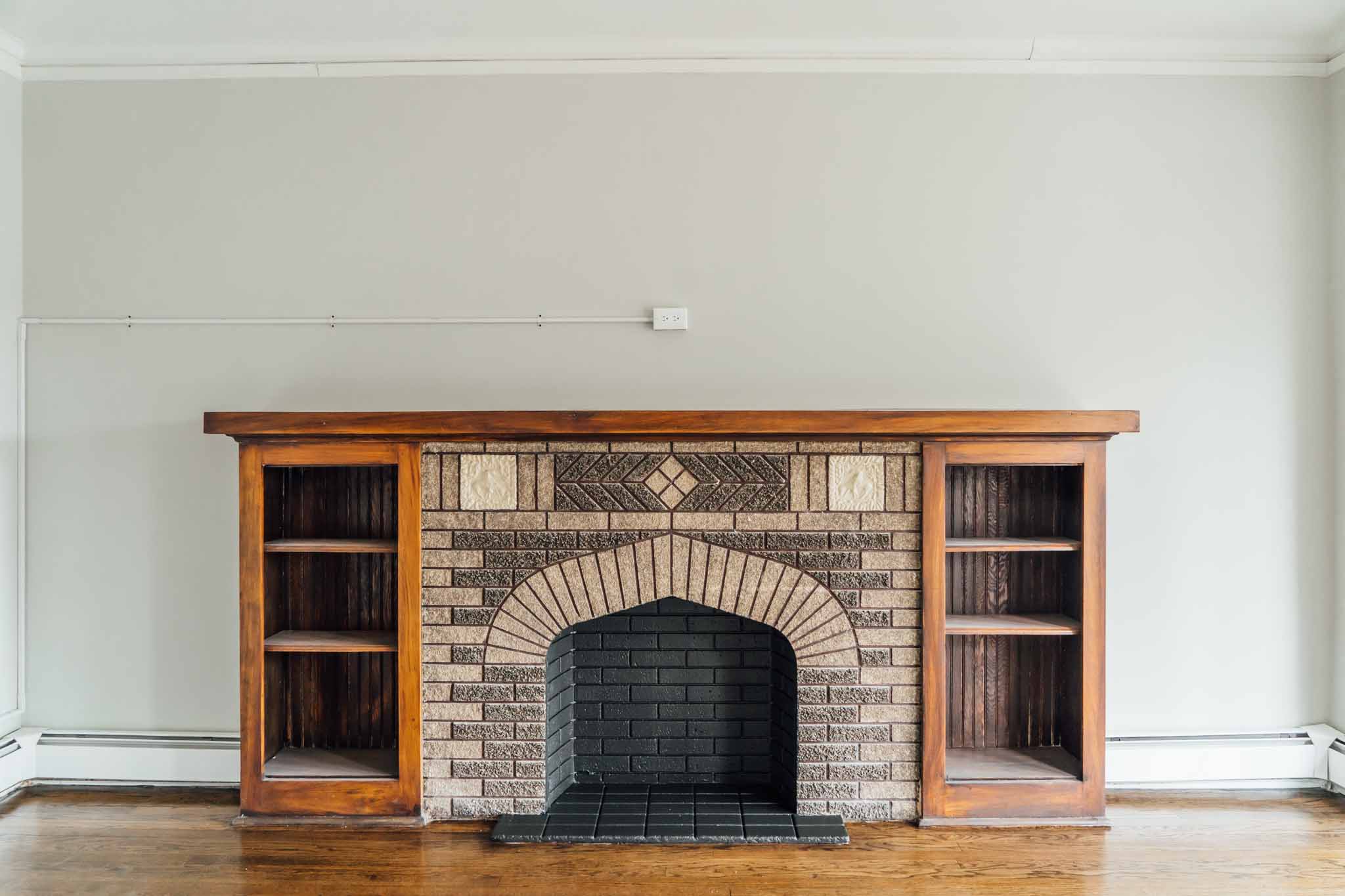 the living room has a brick fireplace and two bookcases