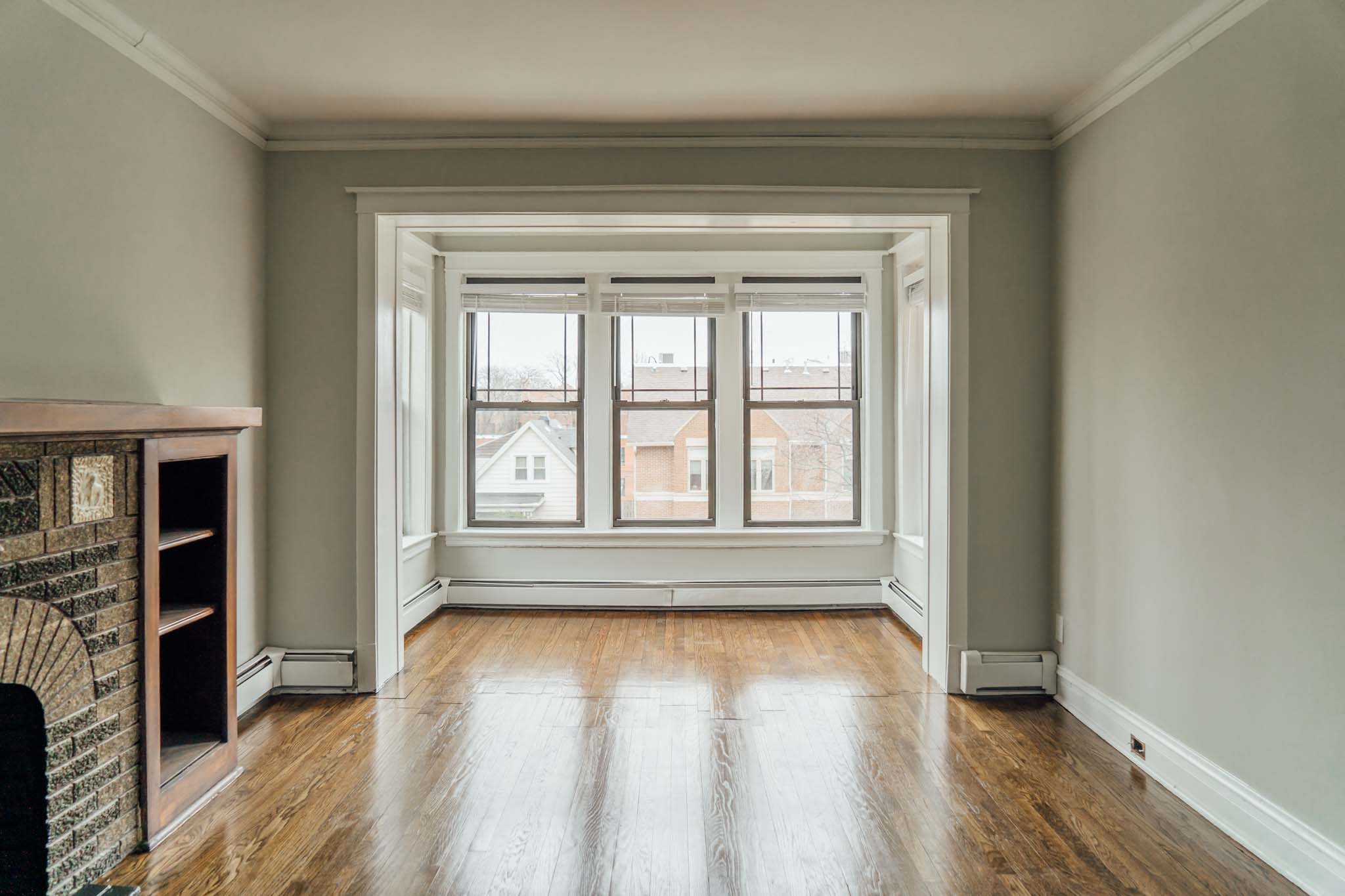an empty living room with a large window and wood floors