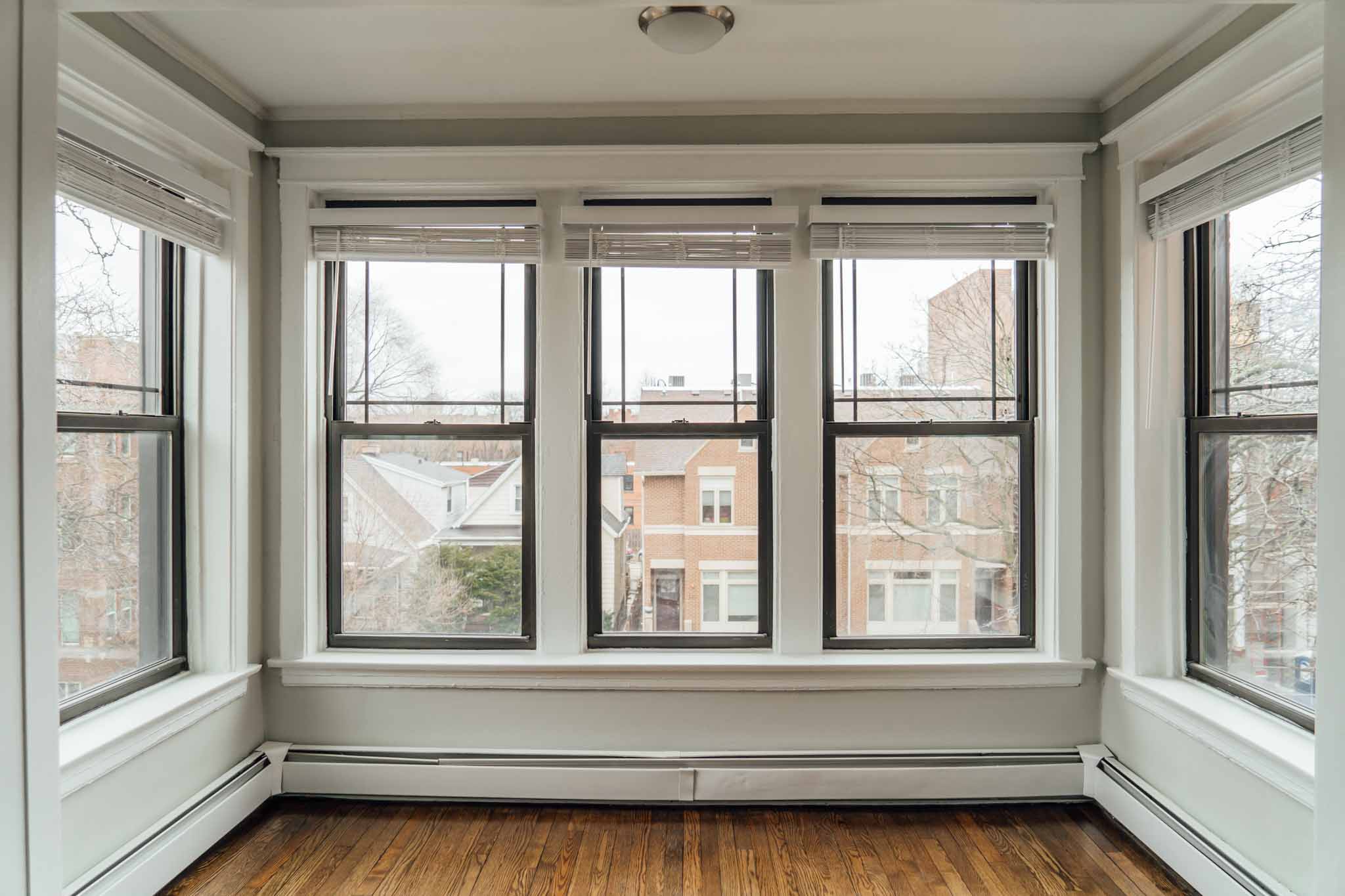a living room with four windows and a wood floor
