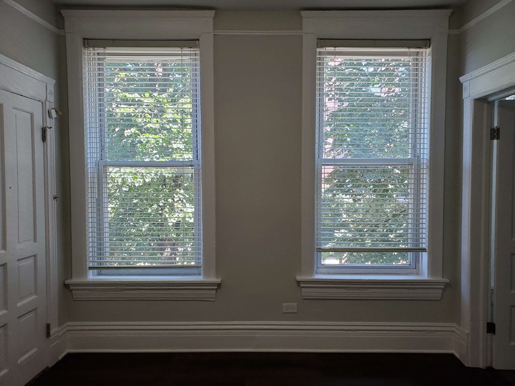two windows in a room with white walls and a door