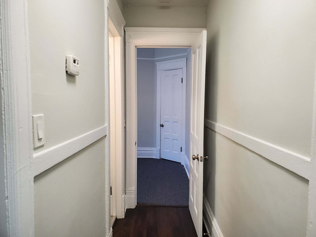a small hallway with a white door and a door to a closet