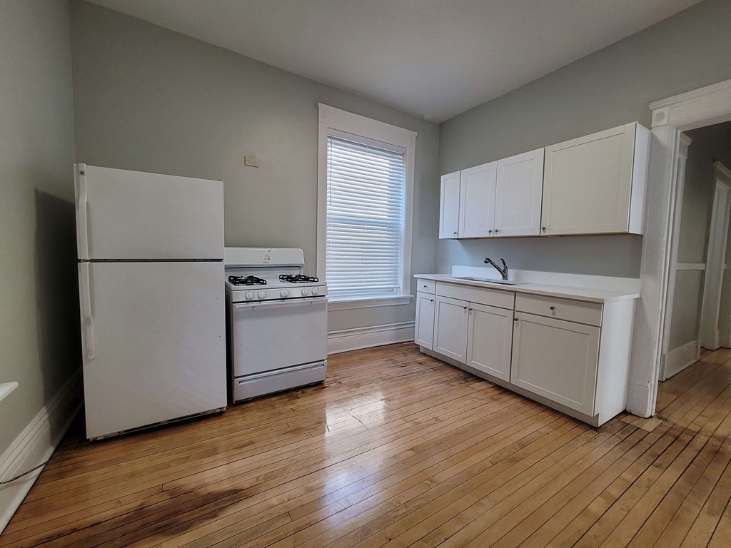 a kitchen with white appliances and a wood floor