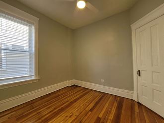 an empty bedroom with wooden floors and a white door