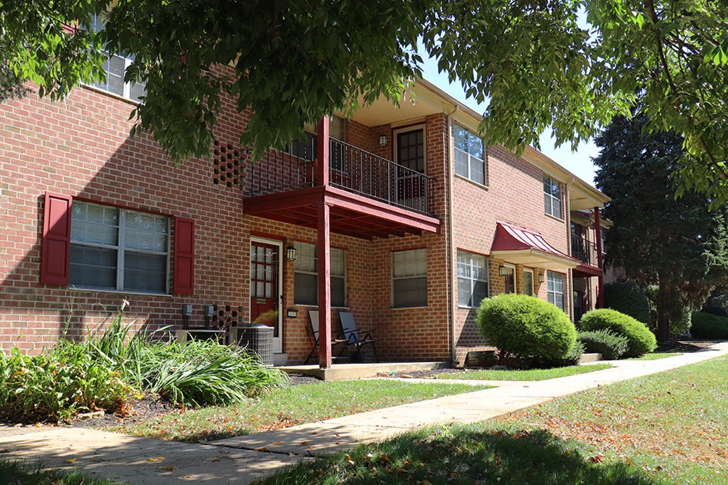 a brick house with a red porch and a tree