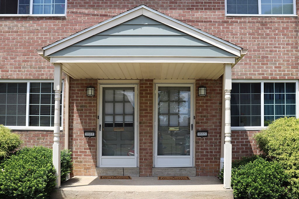 the front door of a brick house with a porch