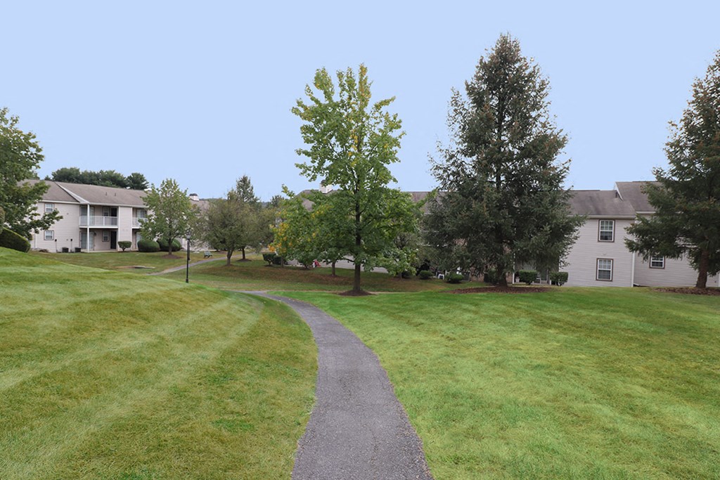 a path through a grassy area with houses in the background