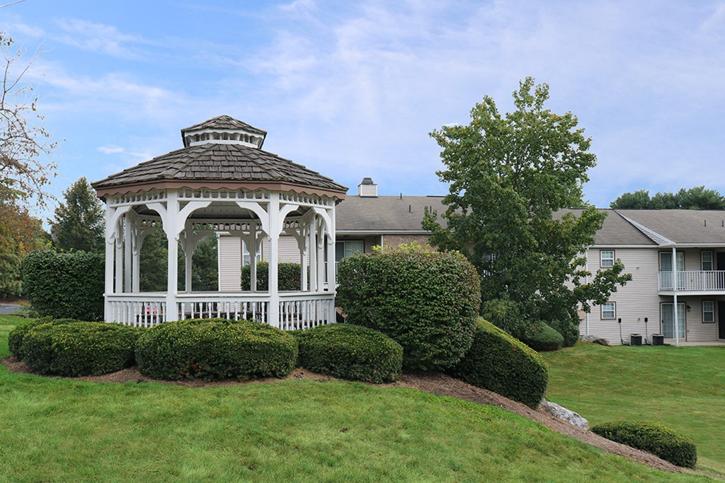 a white gazebo on a lawn in front of a house