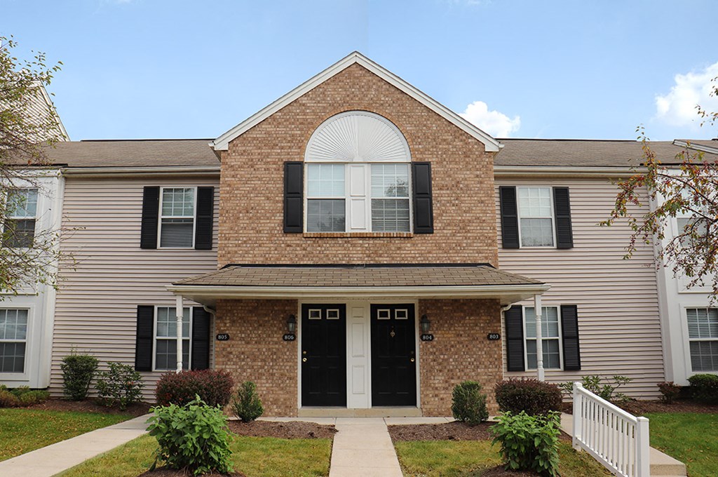 the front of a brick house with a sidewalk in front of it