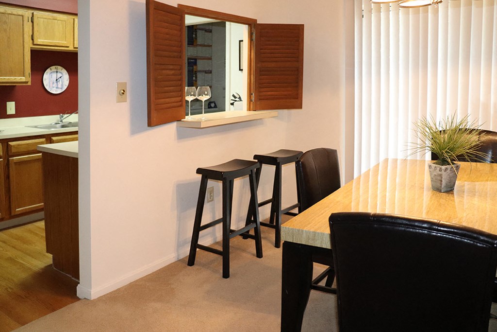 a dining room and kitchen with a table and stools