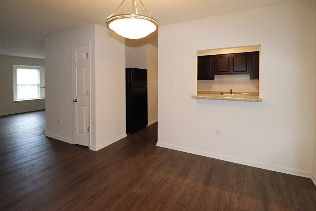 an empty living room with wood floors and a kitchen