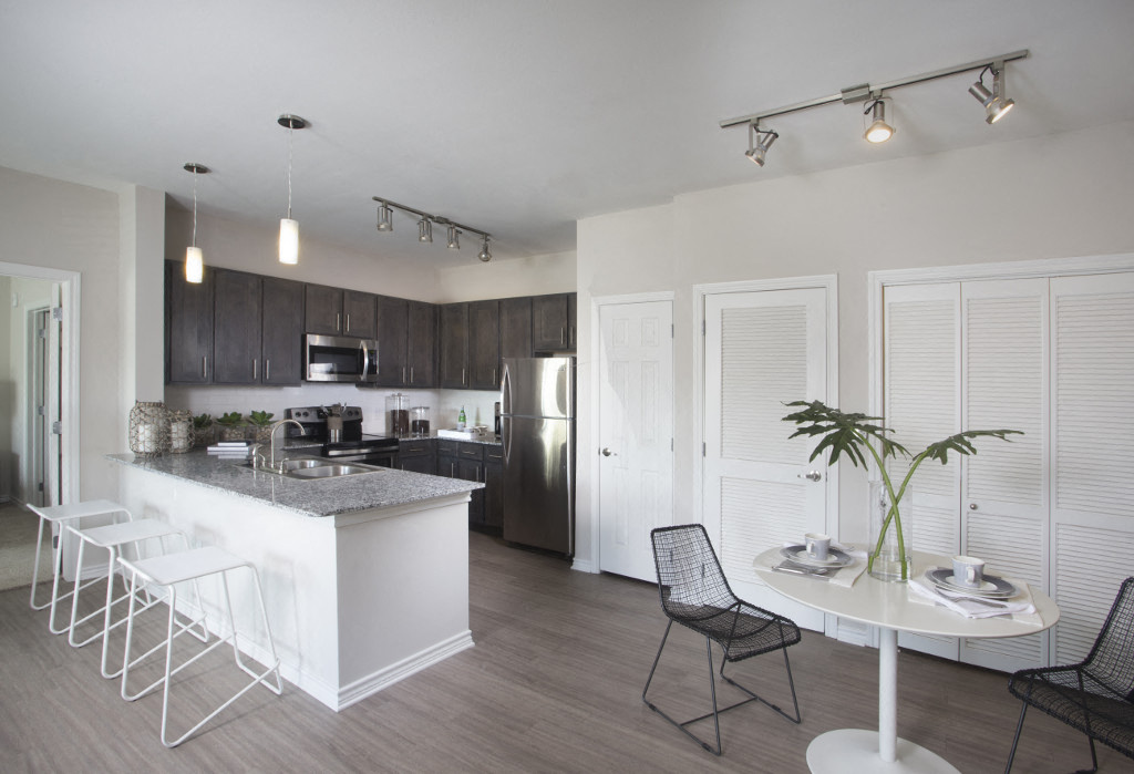 an open kitchen and dining area with a table and chairs and a refrigerator and microwave