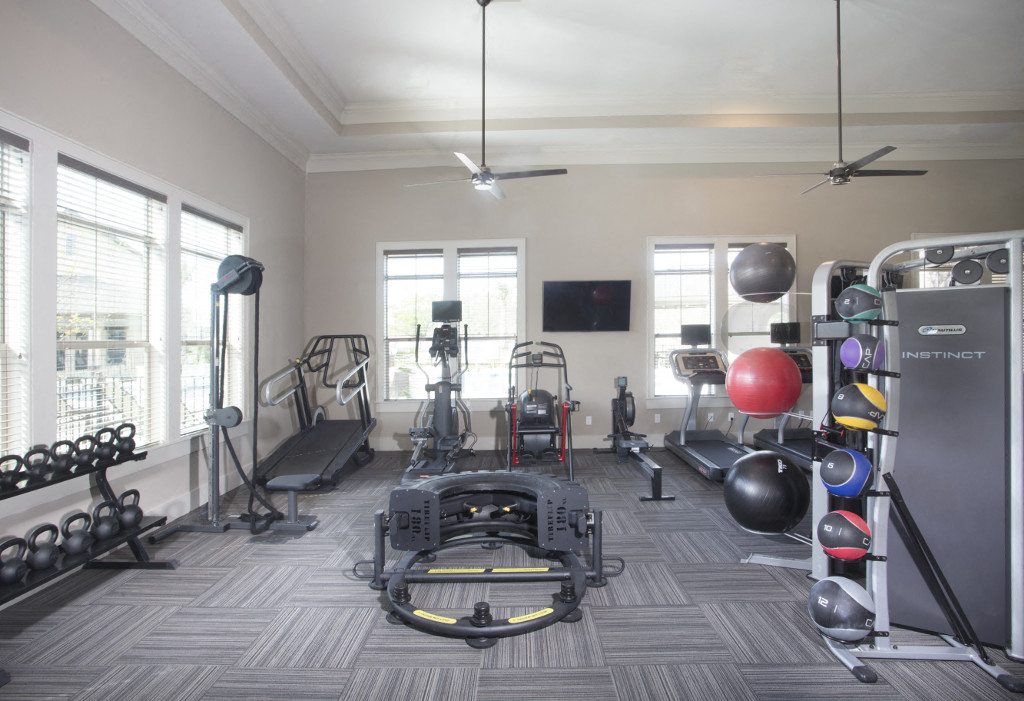 a home gym with a lot of equipment and windows