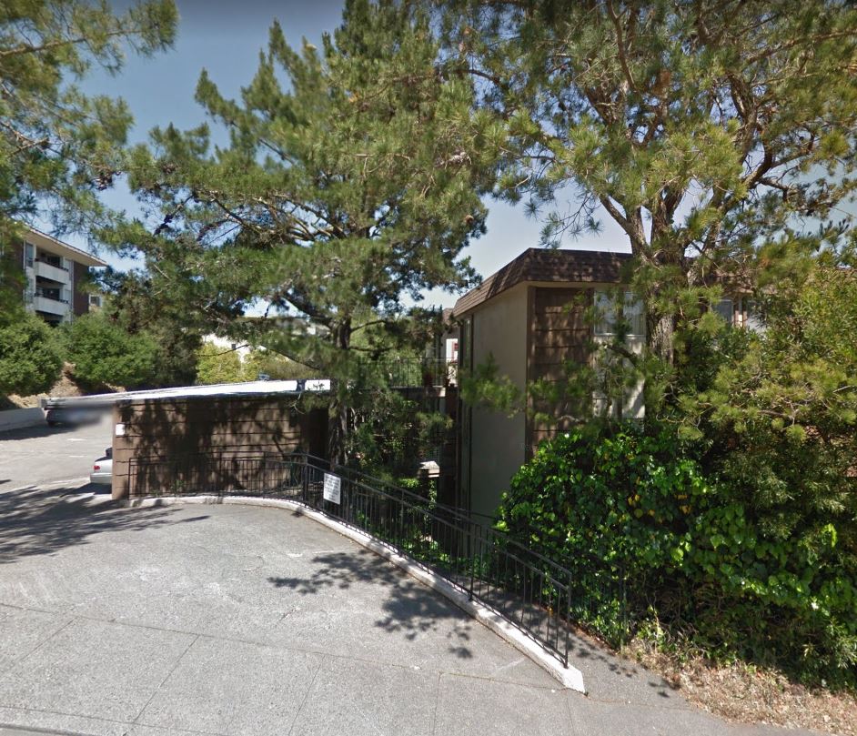 A small building is surrounded by a fence and trees.