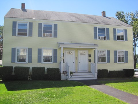 A yellow house with a white door and windows.