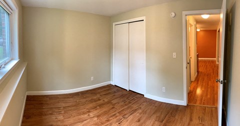 A room with a white door and a wooden floor.