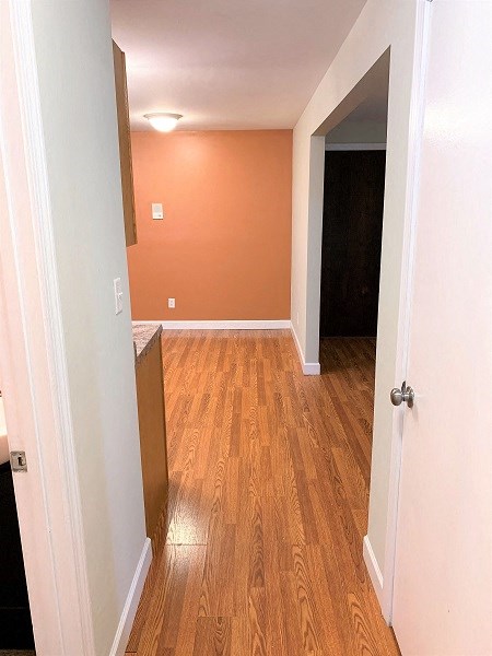 A hallway with a wooden floor and white walls.