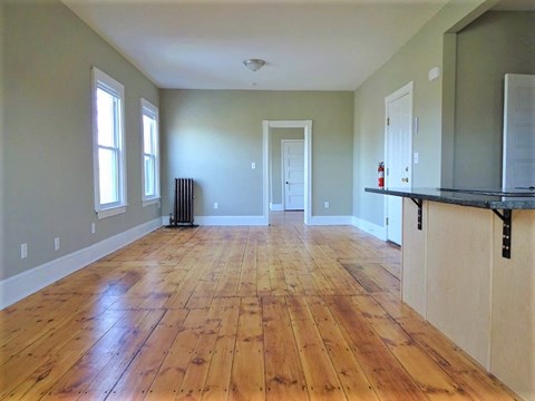 A room with wooden floors and a black counter.