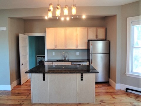 A kitchen with a black counter top and white cabinets.