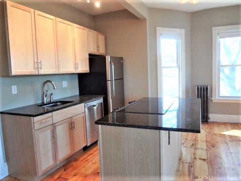 A kitchen with wooden cabinets and black countertops.