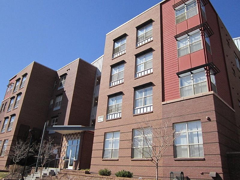 A red brick building with a tree in front.
