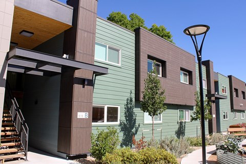 A modern building with a green exterior and a brown entrance.