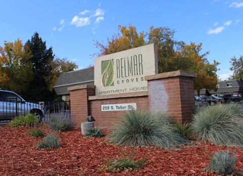 A sign for Belmar Apartments is displayed in front of a building.