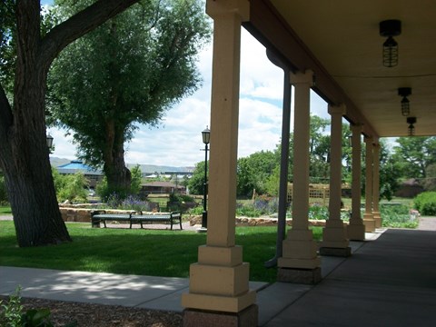 A porch with columns and a bench under a tree.