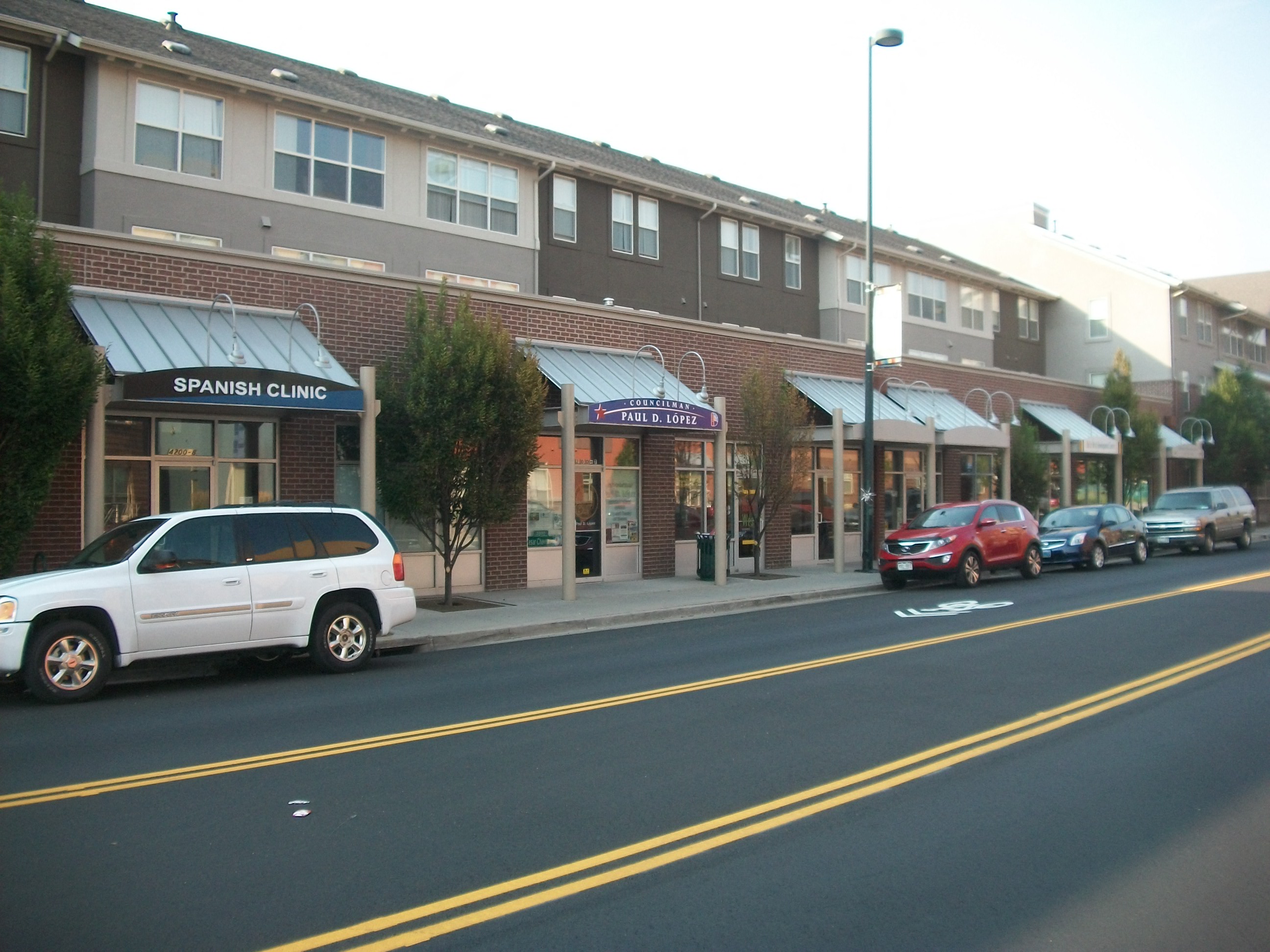 A white SUV is parked in front of a Spanish clinic.