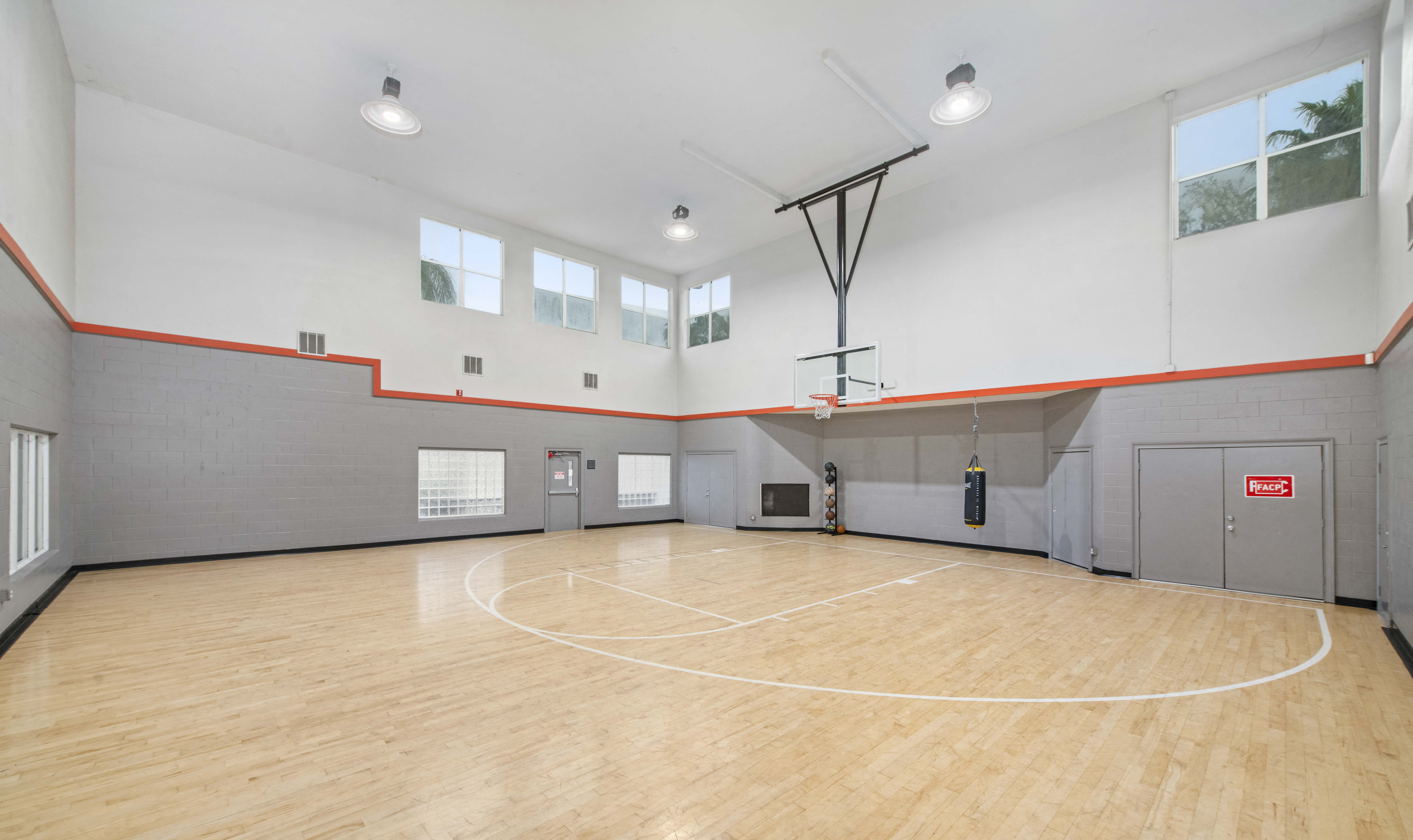 the spacious gym has a hardwood floor and a basketball court