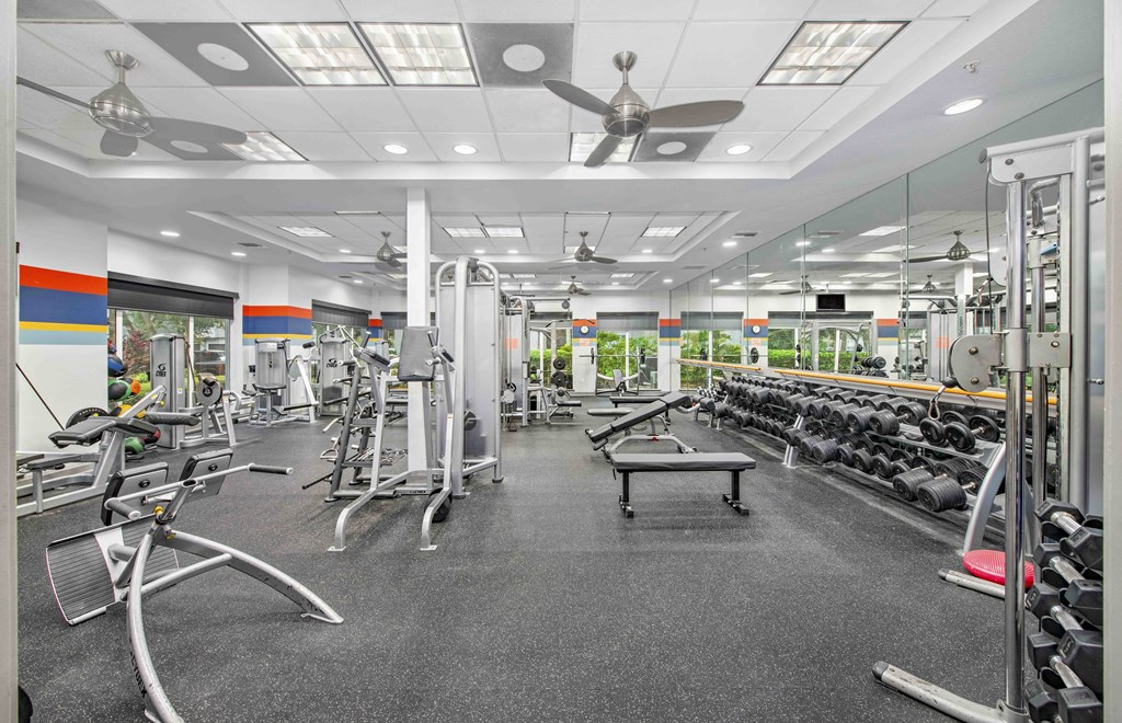 a gym with weights and cardio equipment and a ceiling fan