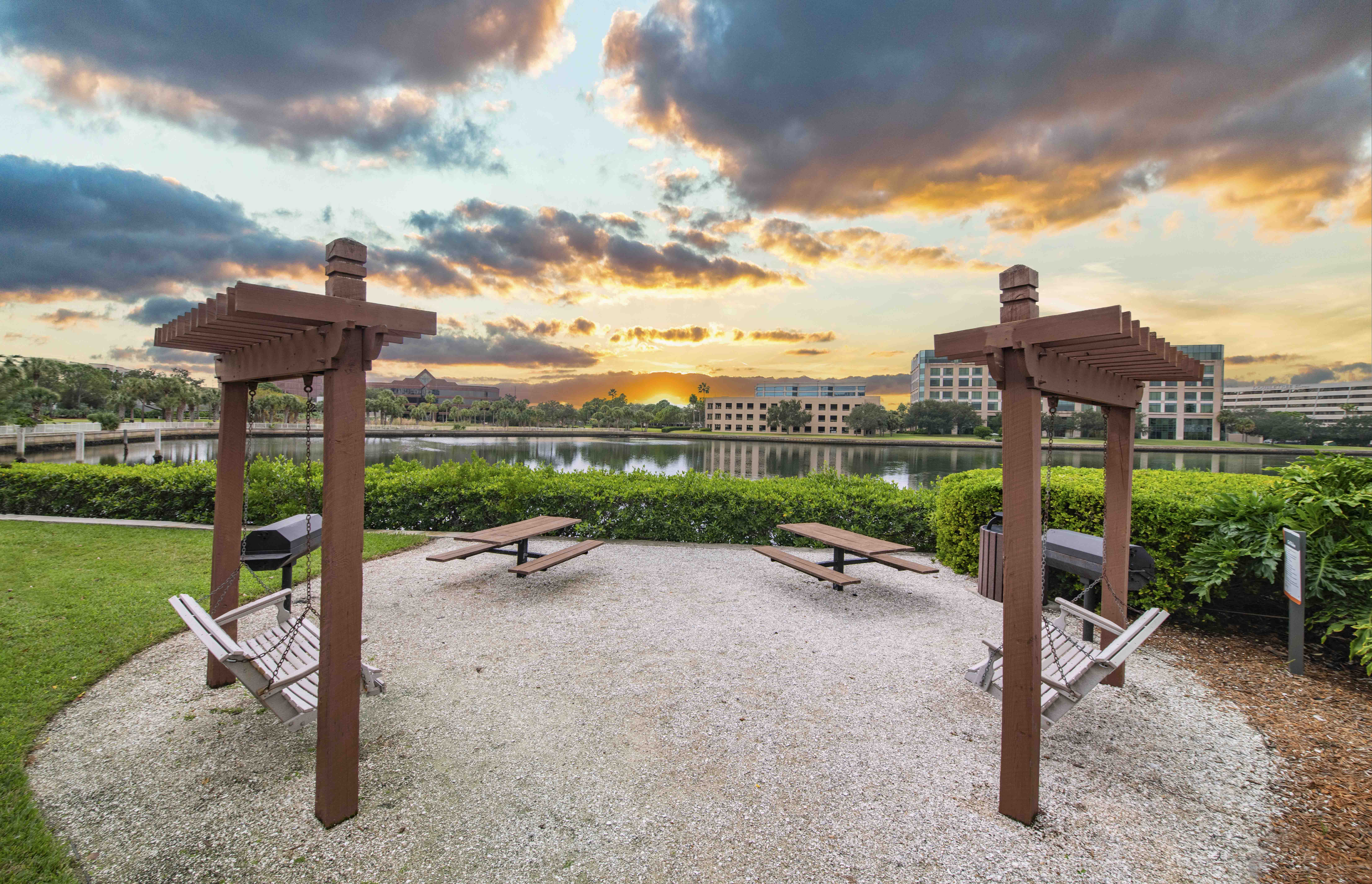 a park with benches and a lake at sunset