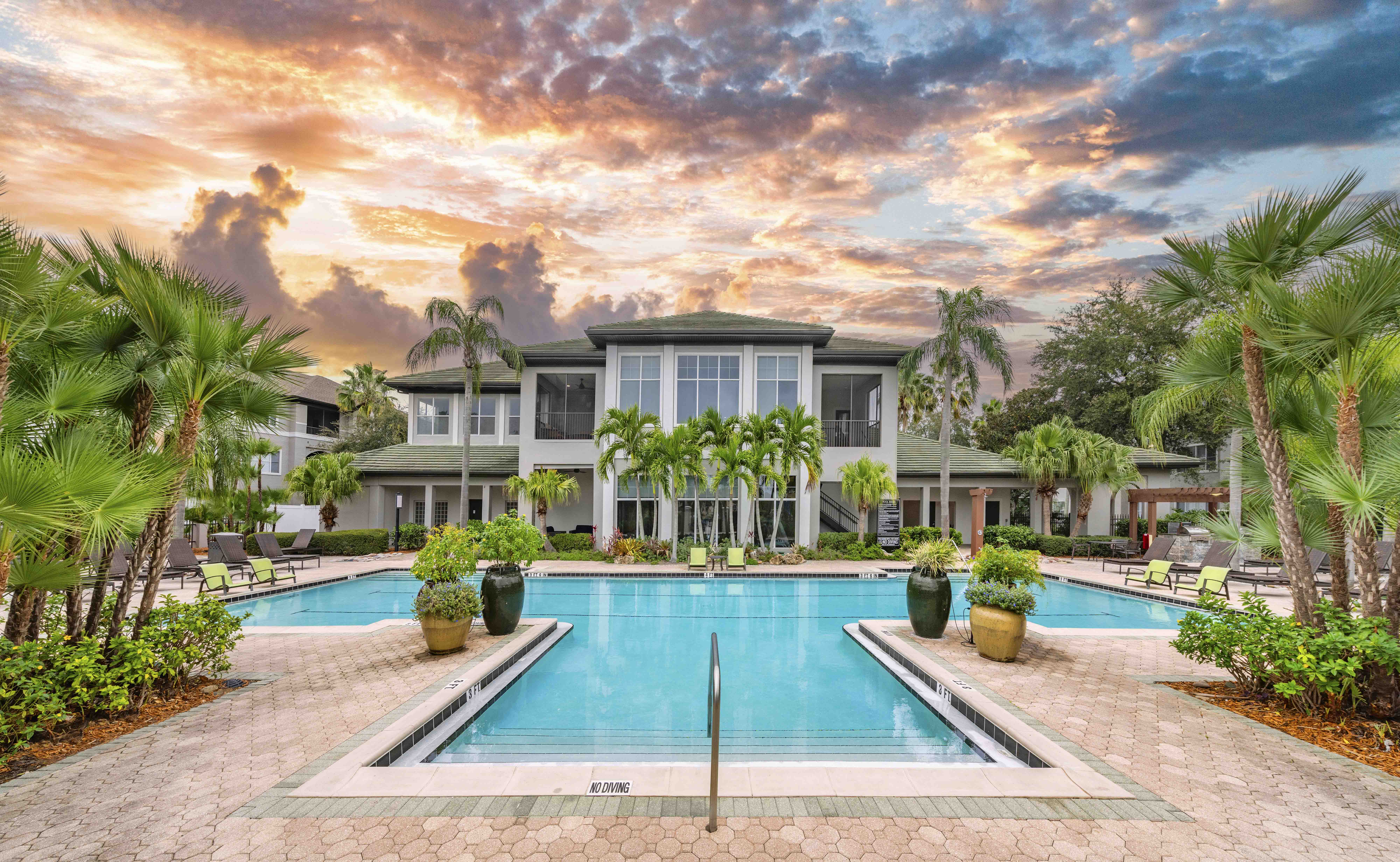 a large swimming pool in front of a building with palm trees