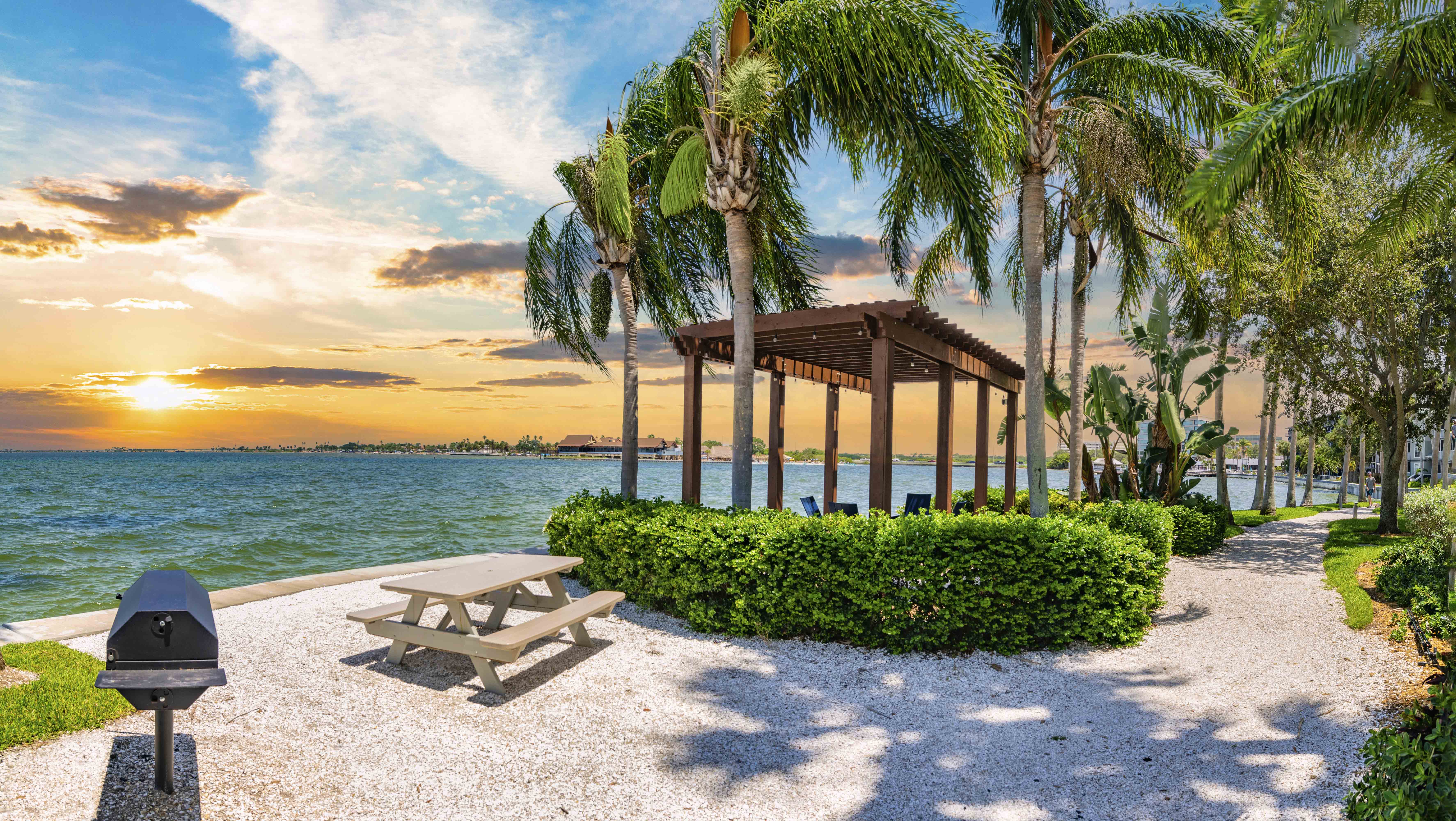 a picnic table and a gazebo on the beach at sunset