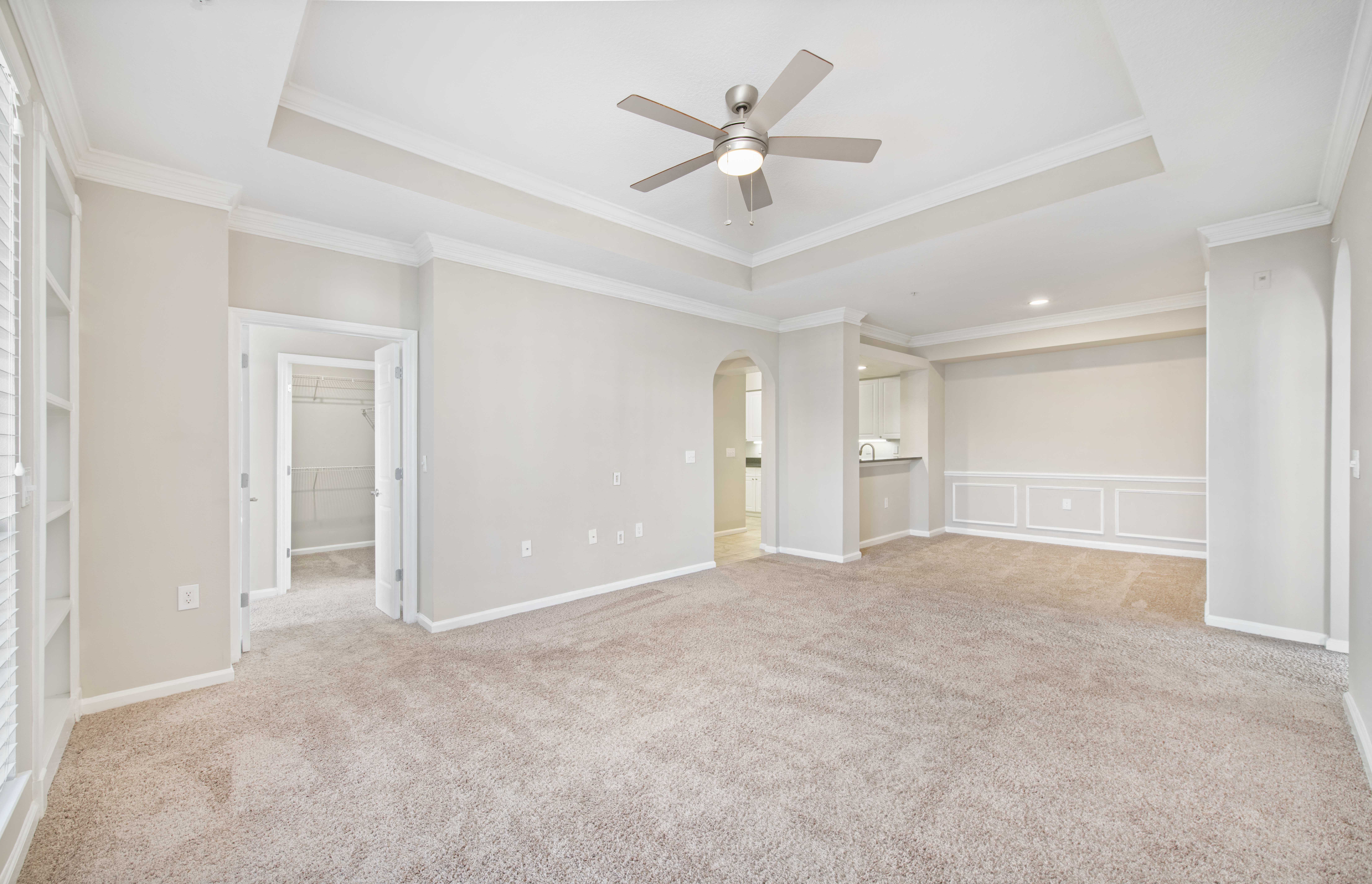 an empty living room with a ceiling fan
