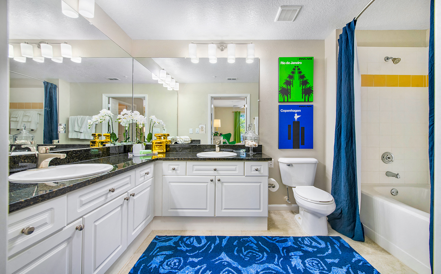 a bathroom with white cabinets and a blue rug