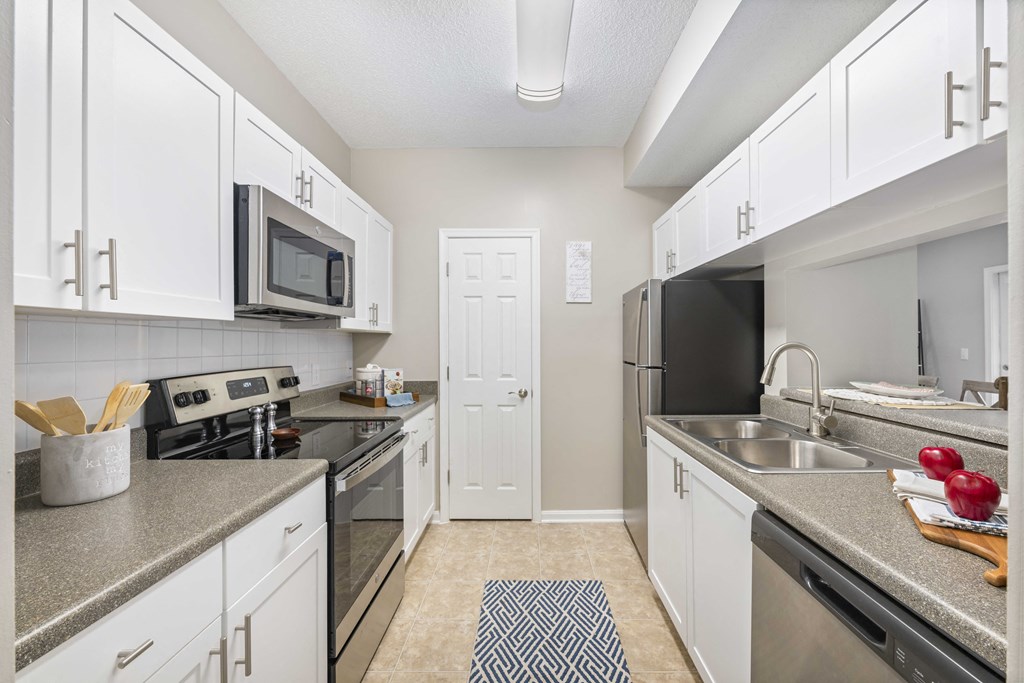 A kitchen with white cabinets and a black refrigerator.