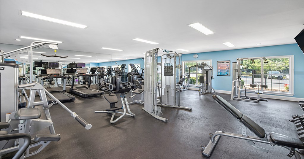 A gym with a variety of equipment including treadmills, weights, and exercise machines.
