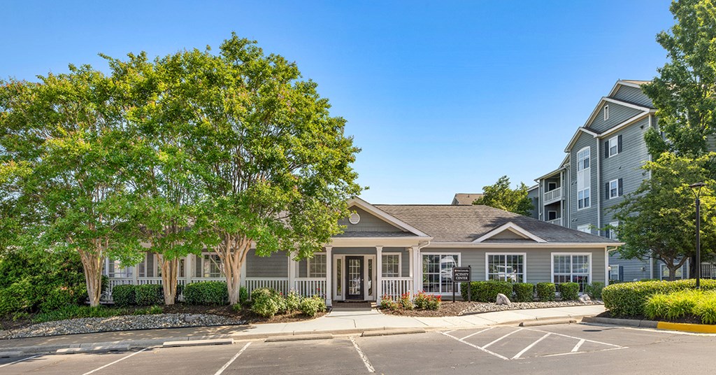 A building with a grey roof and white walls is surrounded by a parking lot.