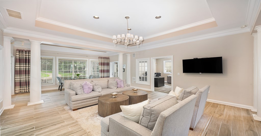A living room with a grey couch and a chandelier.