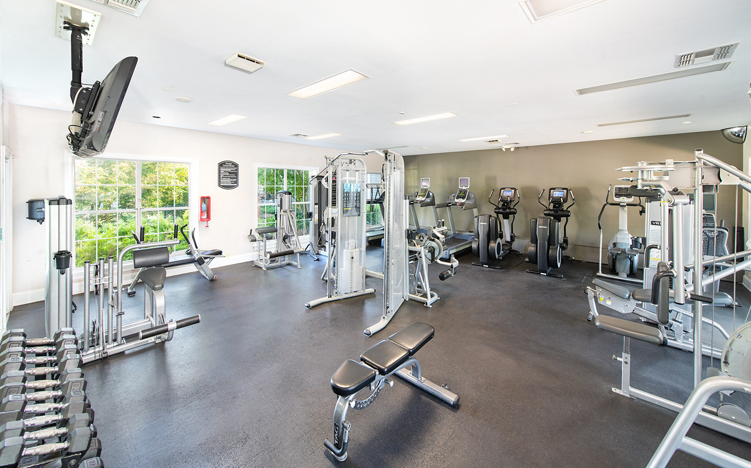 a gym with cardio equipment and weights on the floor