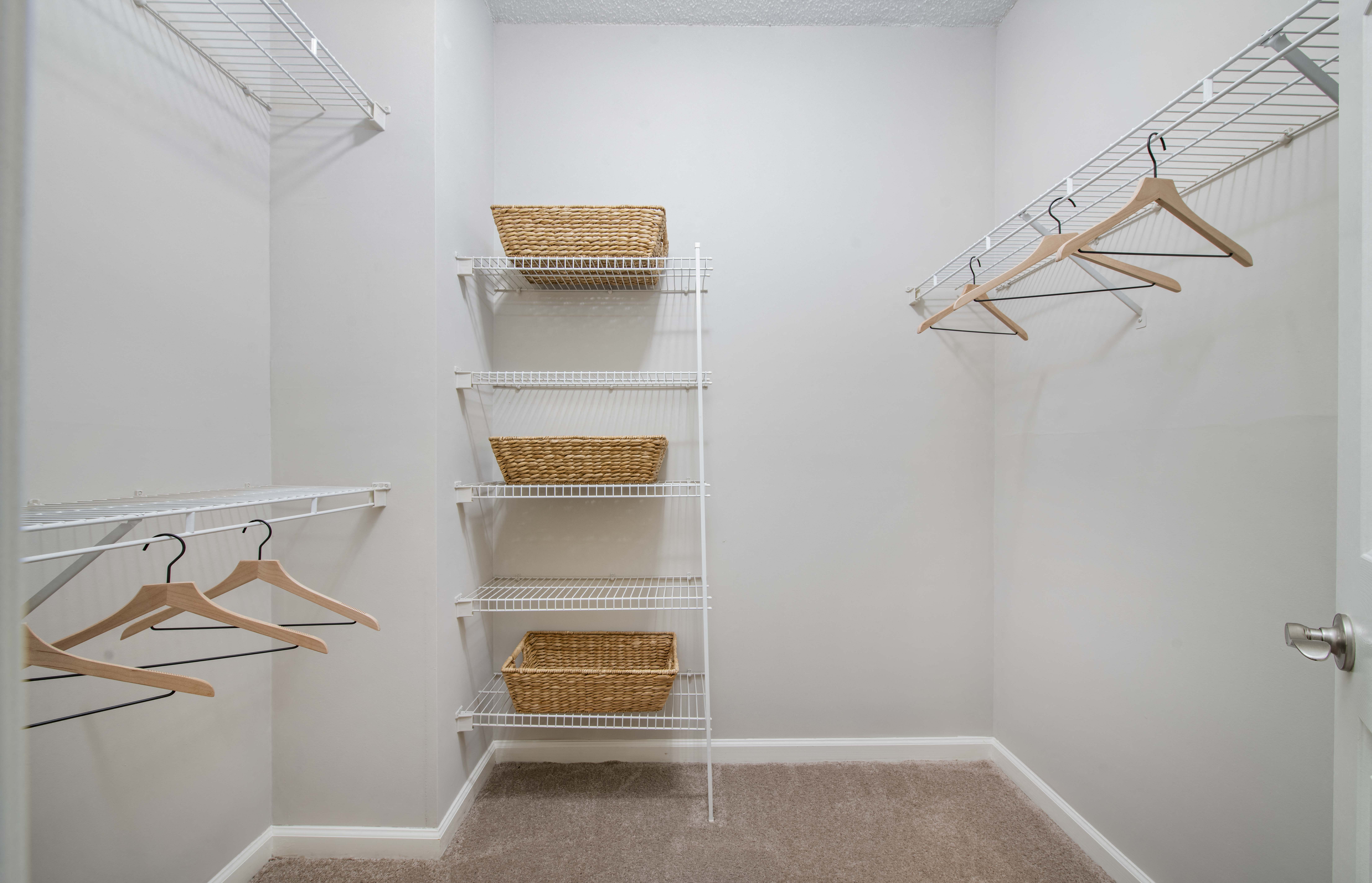 a closet with shelves and racks in a home with white walls