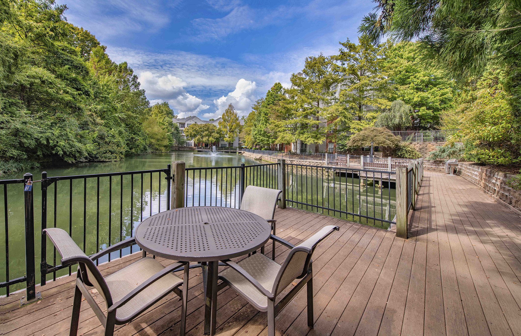 a patio with a table and chairs on a deck overlooking a lake