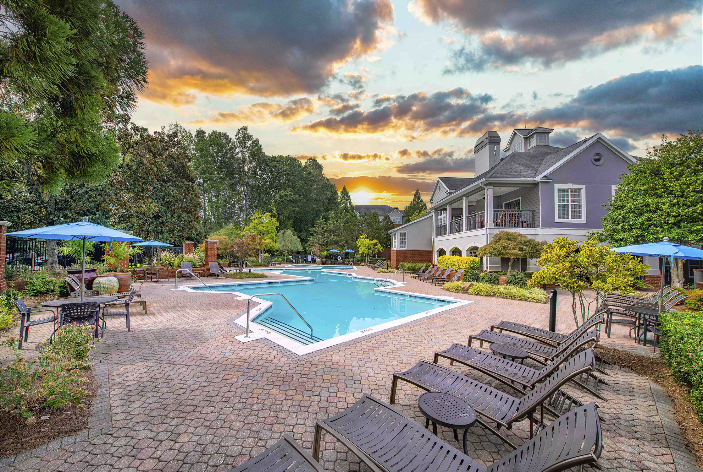 a swimming pool with benches and a house in the background