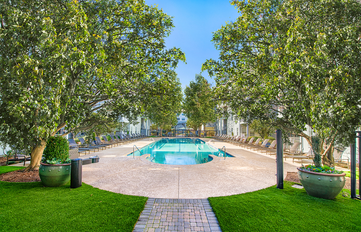 a swimming pool is surrounded by trees and a brick sidewalk