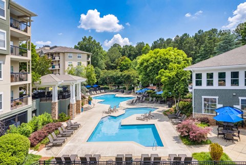 A large swimming pool surrounded by lounge chairs and umbrellas.