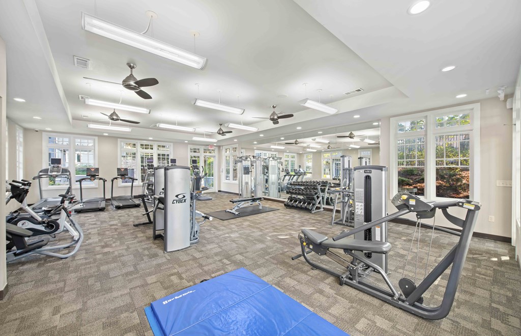 a gym with weights and cardio equipment in a building with windows