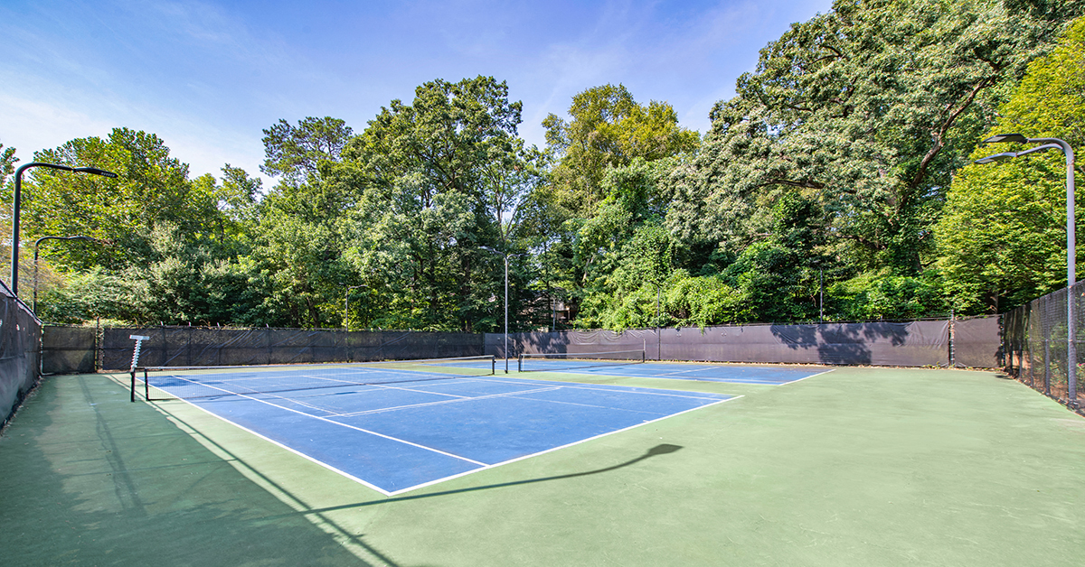 a tennis court with trees in the background on a sunny day