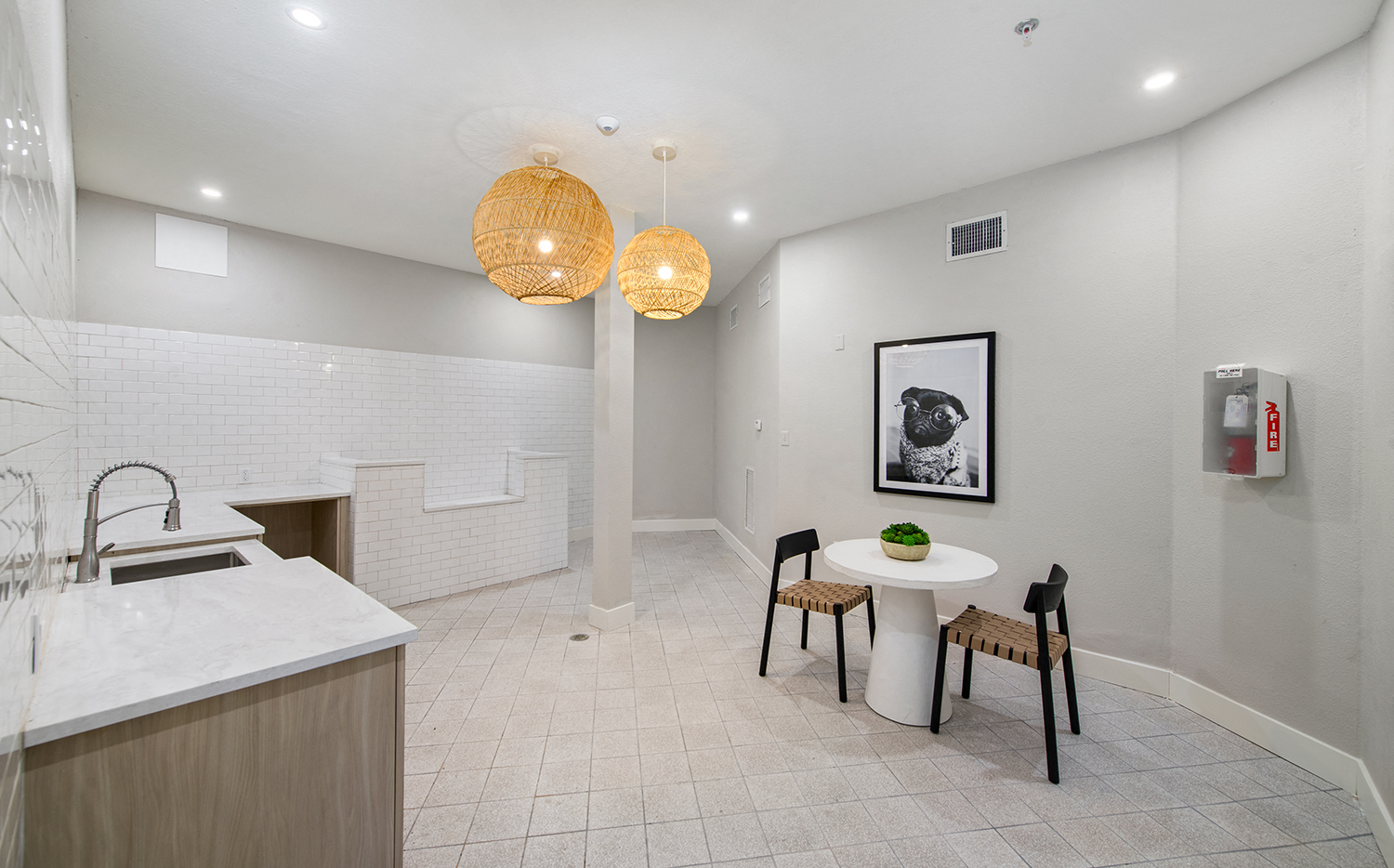 a dining room with a white table and chairs and a kitchen with a sink